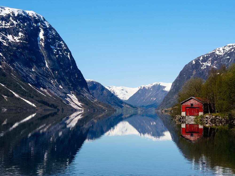 Norwegischer Fjord mit Bergen, ruhigem Wasser und rotem Haus am Ufer