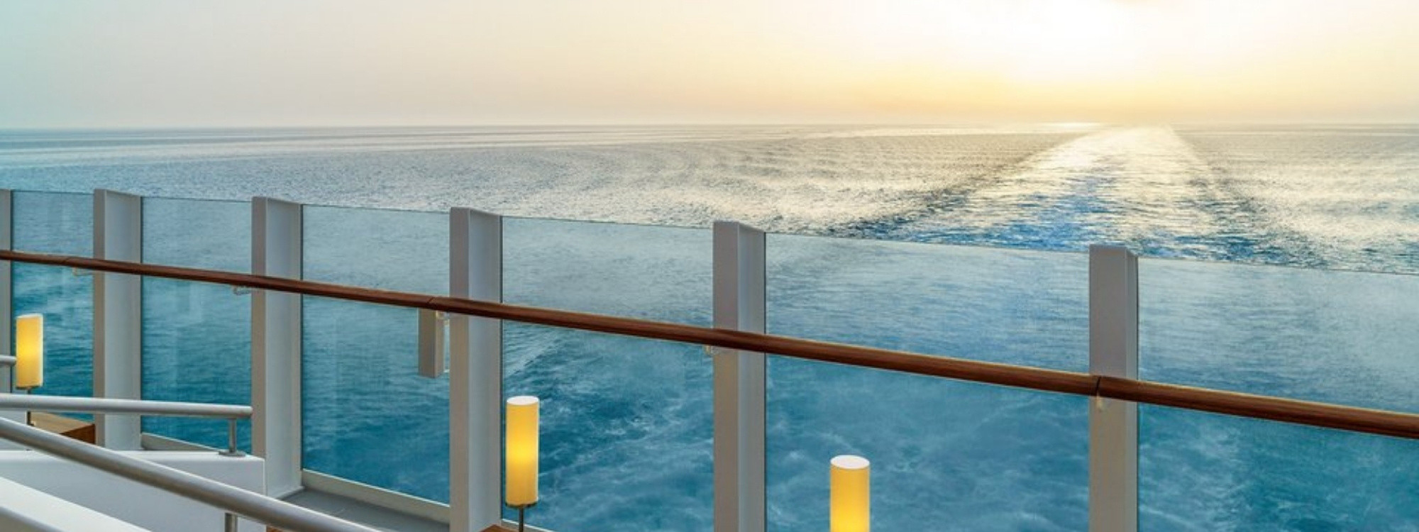Blick vom Heck der AIDAperla auf das offene Meer bei Sonnenuntergang mit ruhiger Atmosphäre
