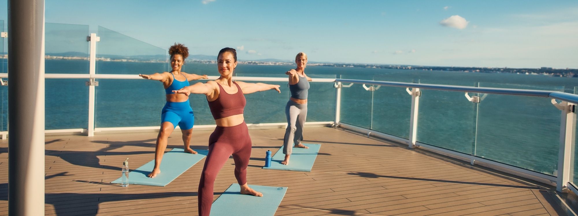 Yoga-Kurs an Deck eines Kreuzfahrtschiffs mit Blick auf das Meer bei sonnigem Wetter