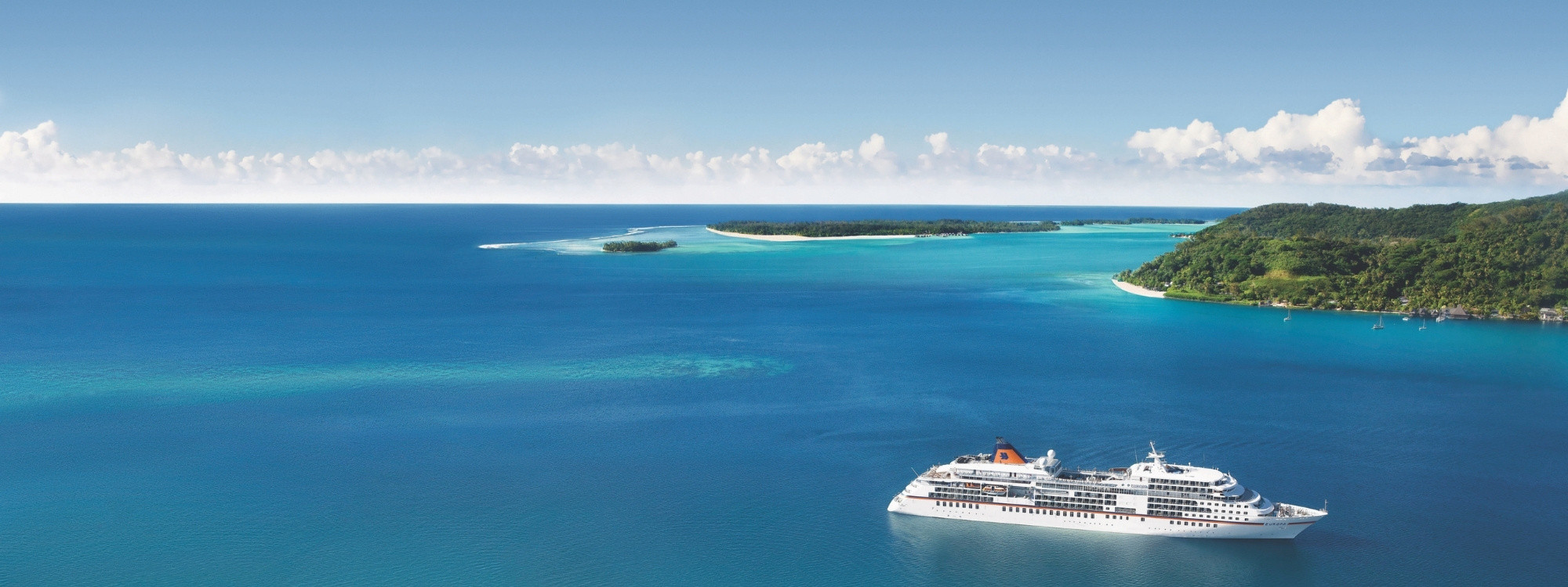 Luxusschiff MS Europa in türkisblauem Meer vor tropischer Inselkulisse in der Südsee